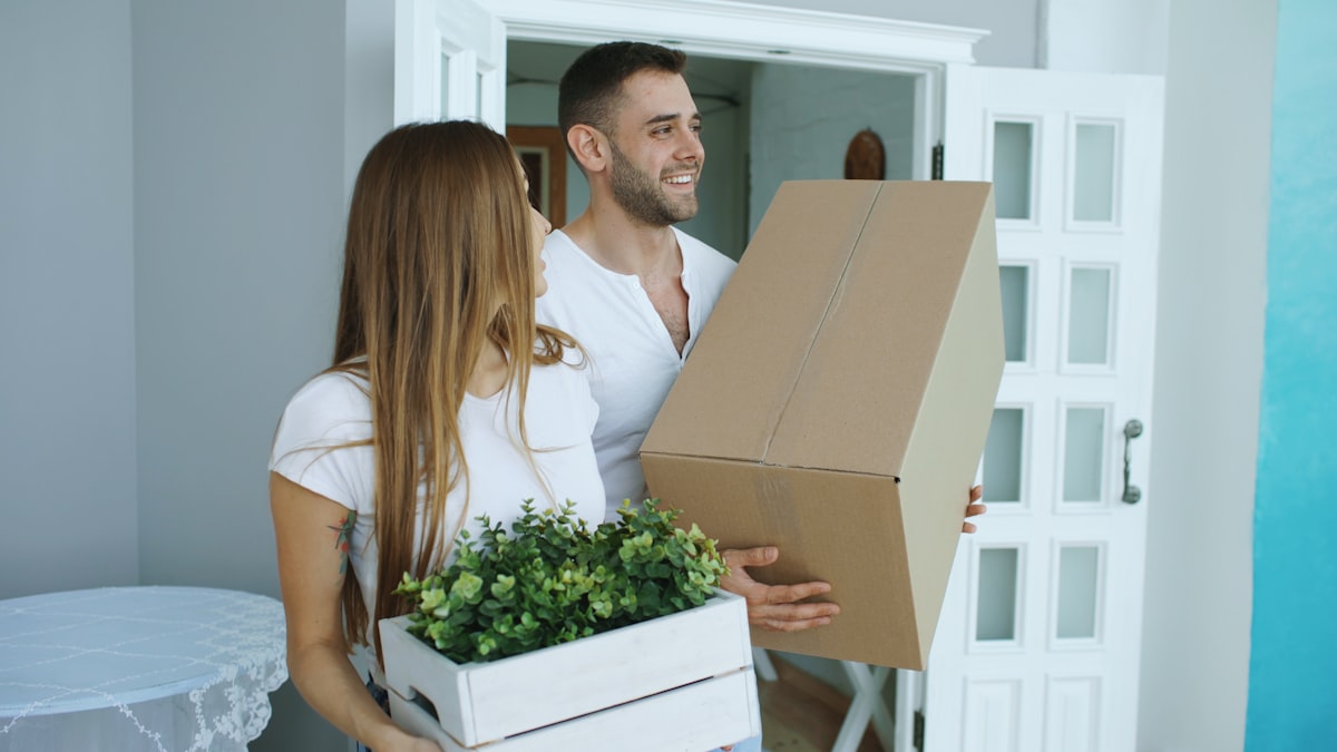 Couple carrying boxes into their new home